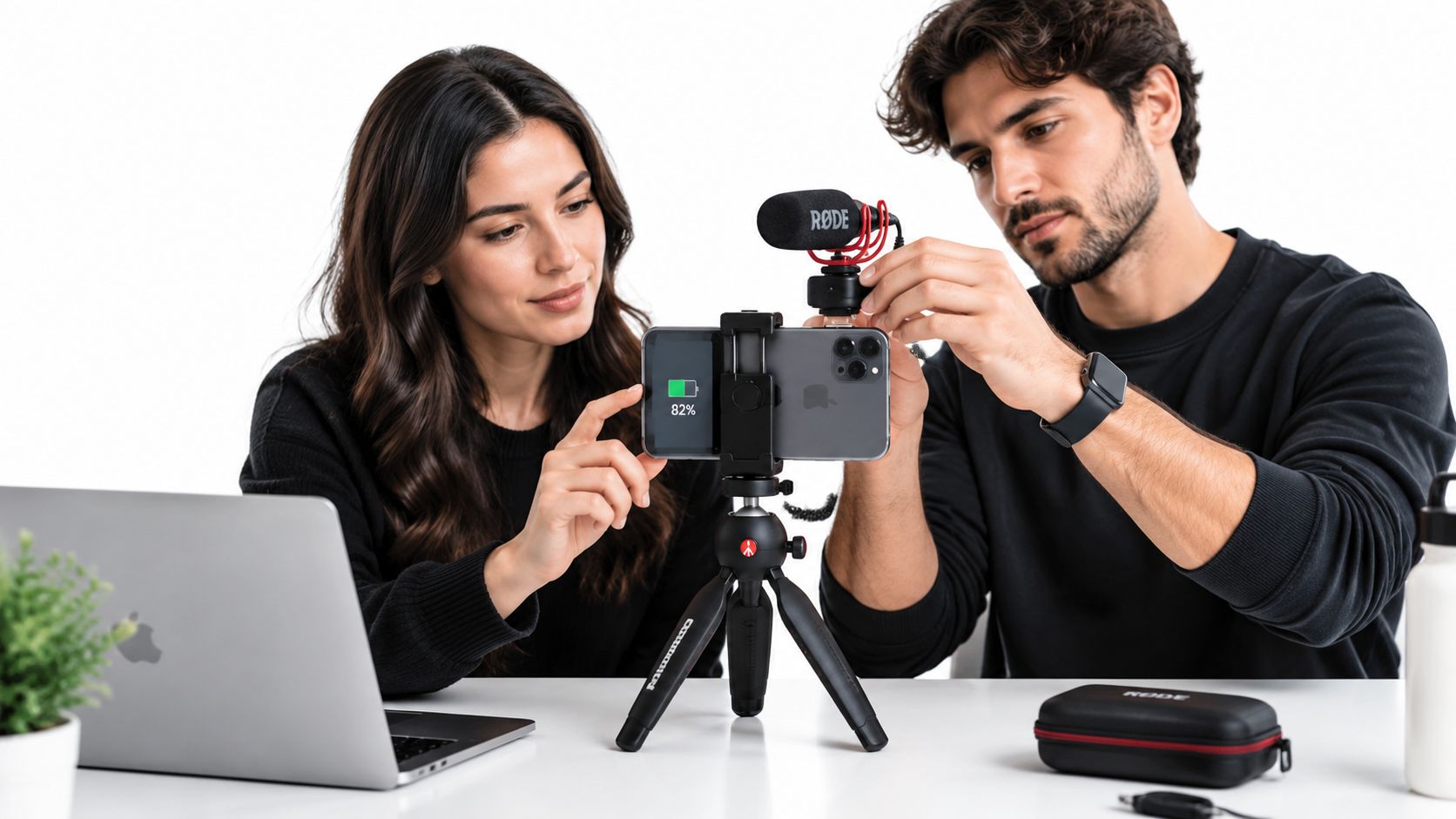 Eine junge Frau und ein Mann richten ein Smartphone auf einem Stativ für Videoaufnahmen ein.